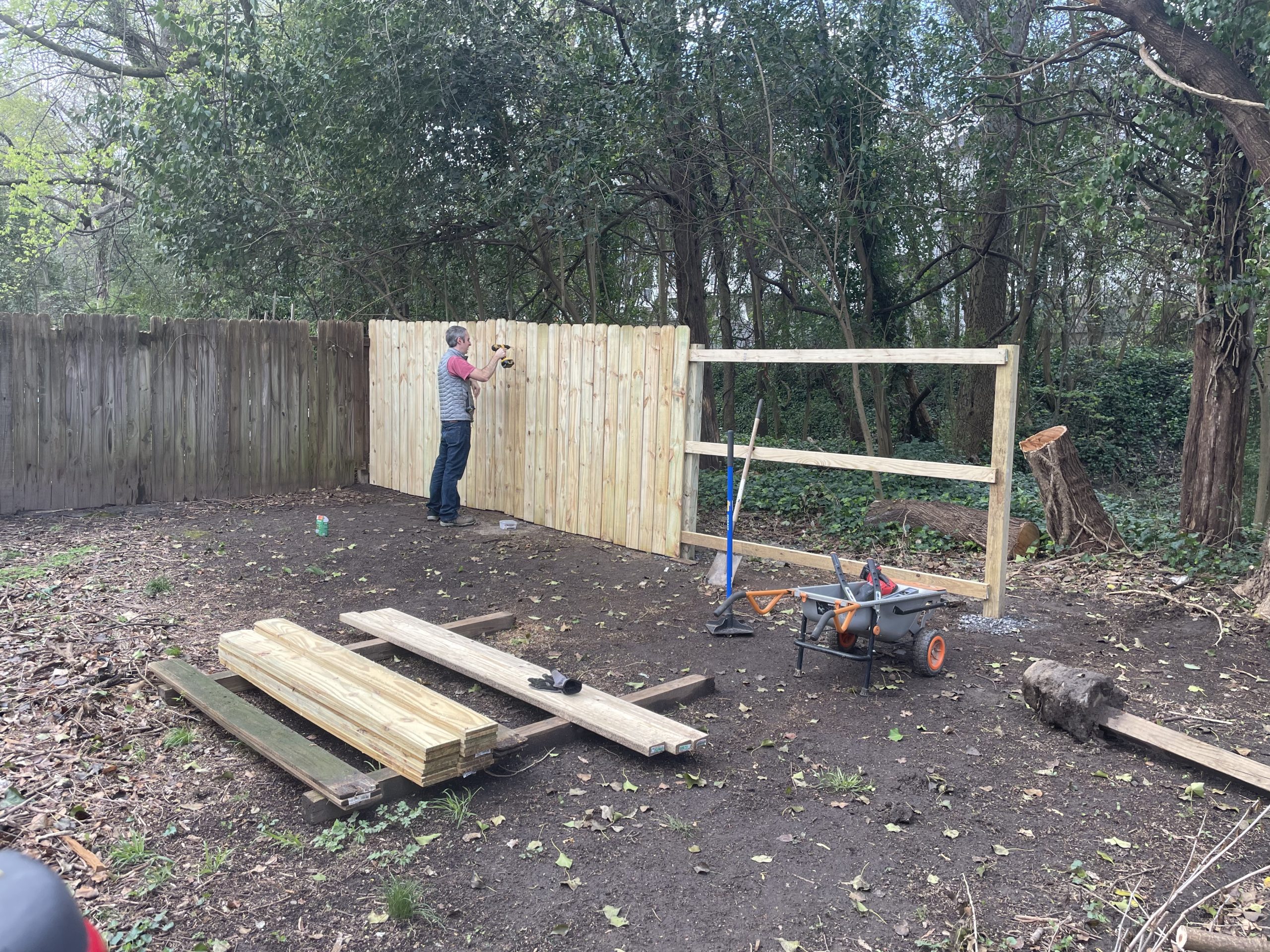 corey using a power drill on the half-finished fence